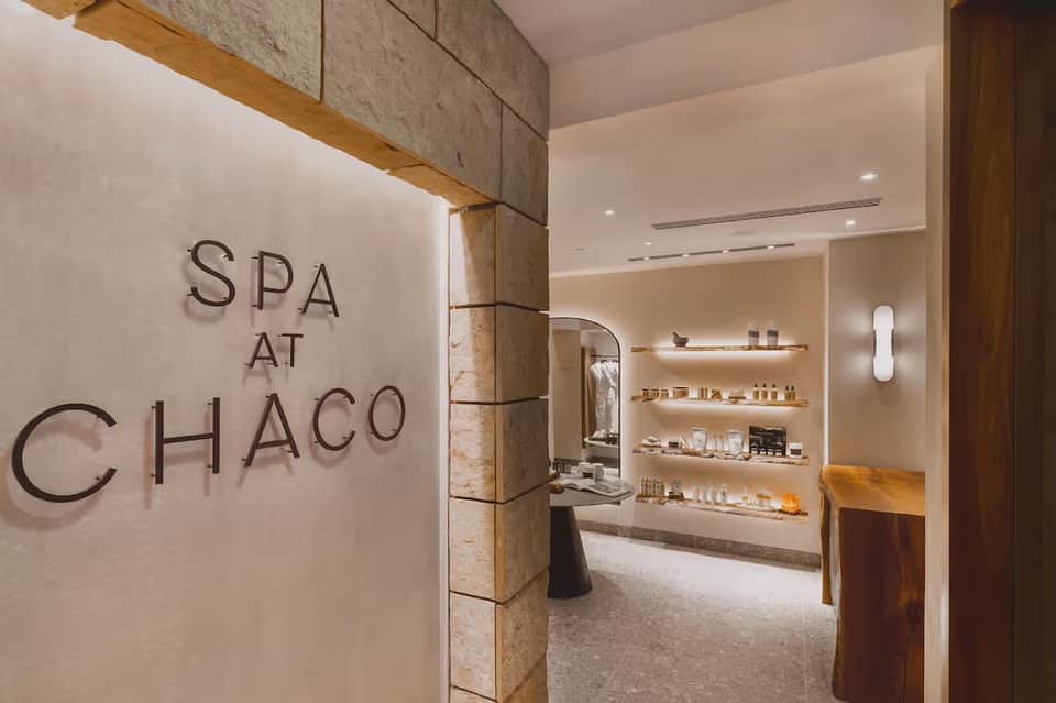 Spa entrance with stone accents, timber beam details, and illuminated shelving displaying spa products