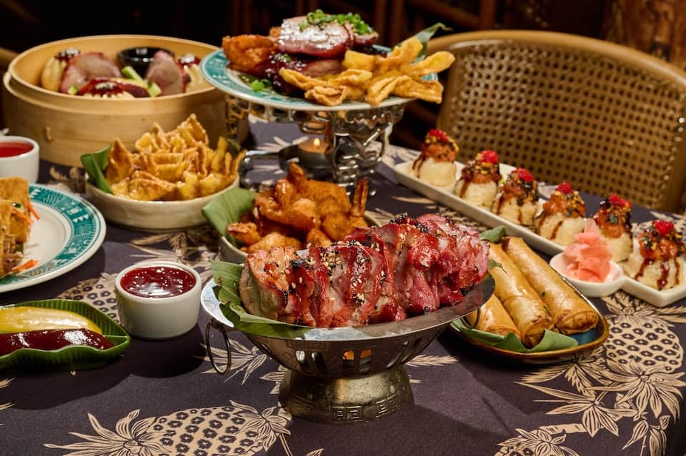 Asian cuisine spread with dumplings, grilled meat, fries, sushi, and decorative plating