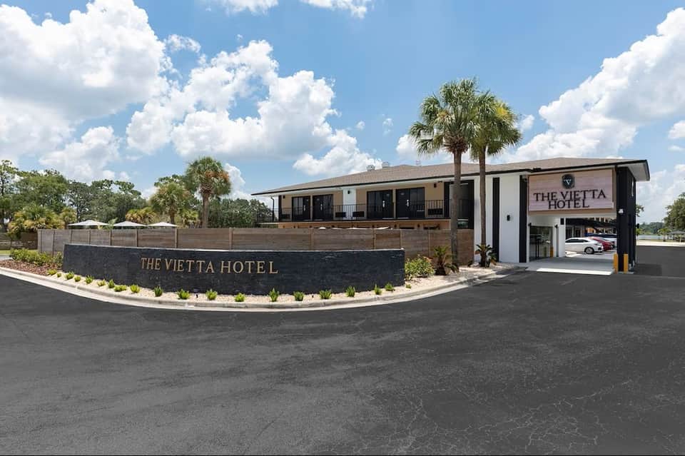 The Vietta Hotel modern exterior with palm trees, contemporary architectural design, and covered entrance