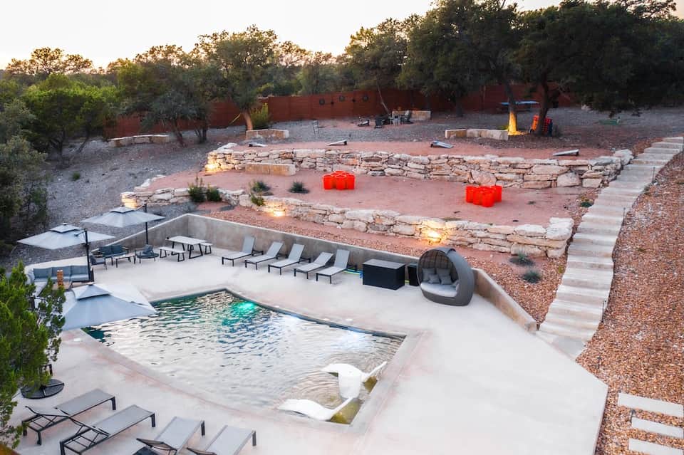 Desert resort with infinity pool, lounge chairs, fire pit, stone amphitheater, and native desert landscaping