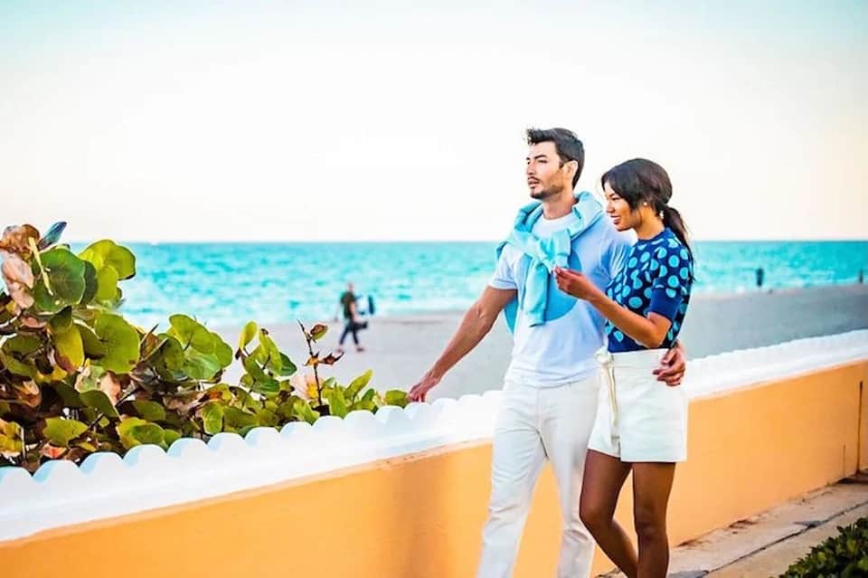 Couple jogging on beach promenade with ocean and sand in background on sunny day
