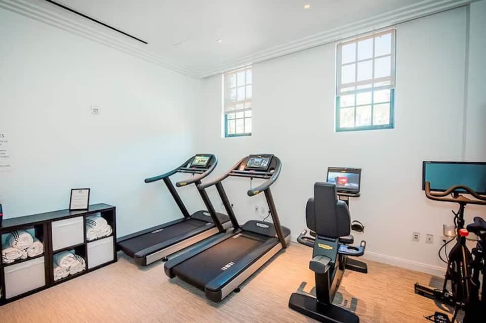 Bright fitness room with treadmills, stationary bike, and natural light from windows