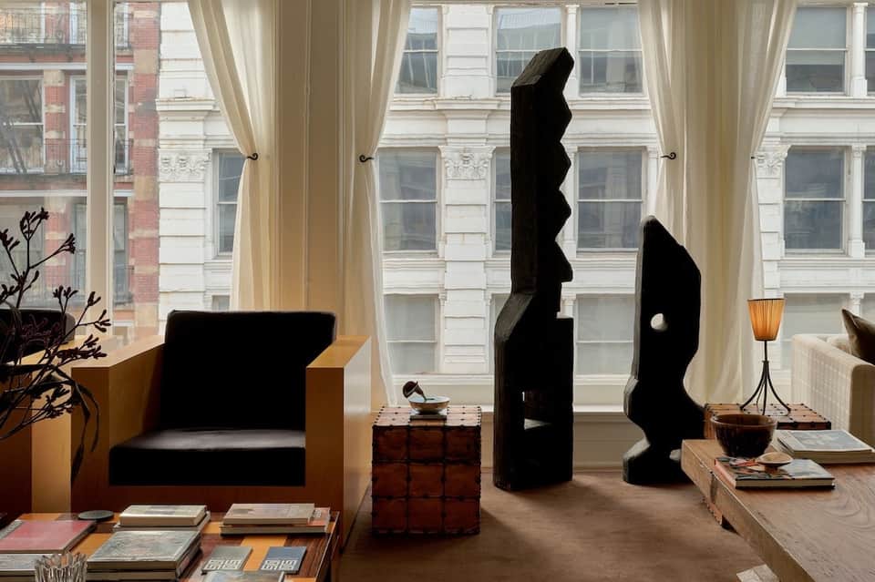 Upscale hotel lounge with black sculptural art, city windows, and contemporary furnishings