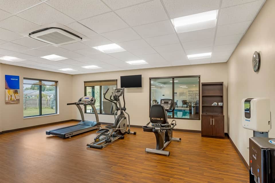 Hotel fitness room with treadmill, elliptical machine, stationary bike, and TV screen