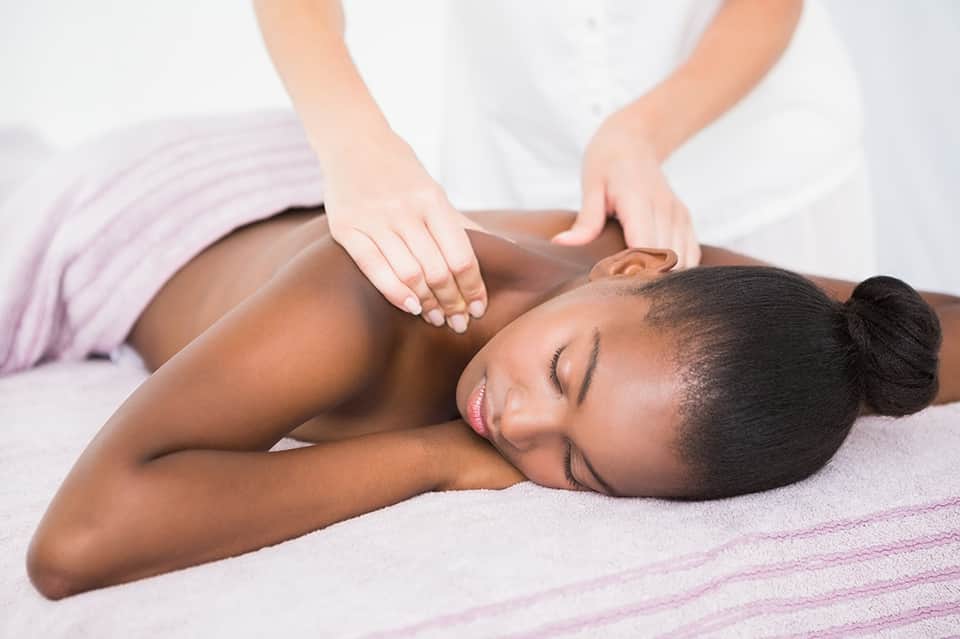 Relaxation massage therapy session with therapist treating client on massage table