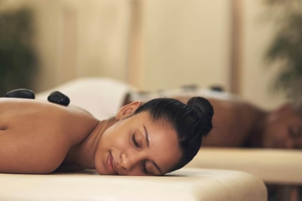 Woman receiving hot stone massage treatment on spa bed with peaceful expression