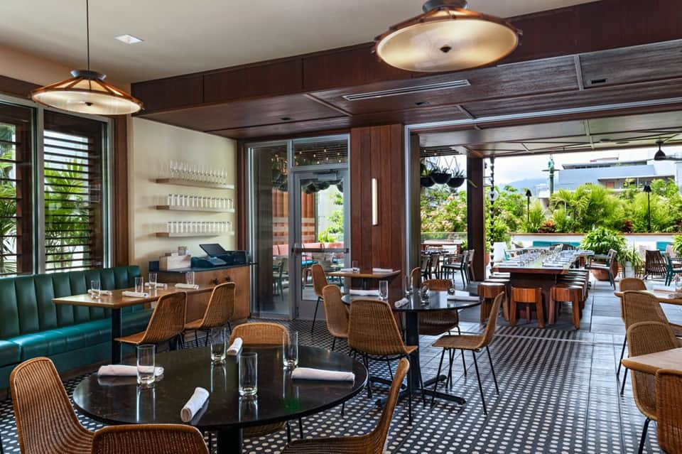 Elegant resort restaurant with teal banquette seating, wicker chairs, and pool views