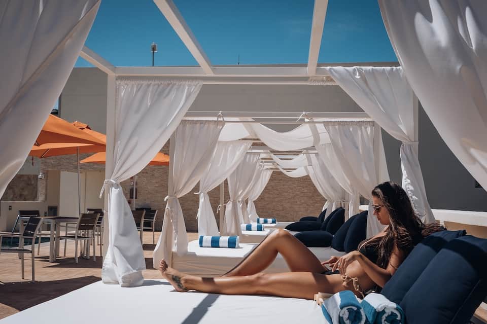 Resort daybed cabanas with white curtains, striped loungers, and ocean views