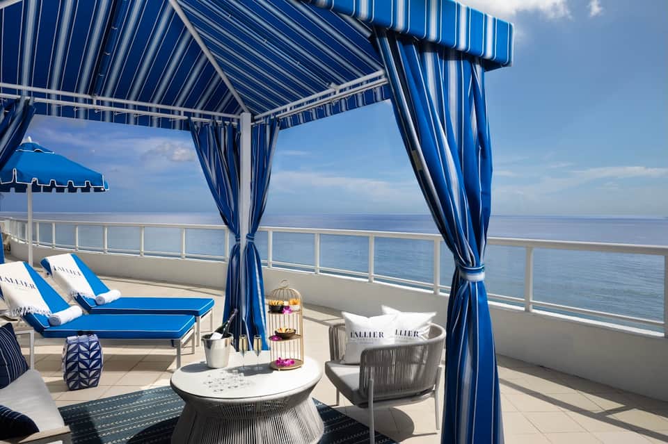 Oceanview balcony cabana with blue striped awning, lounge chairs, and water views
