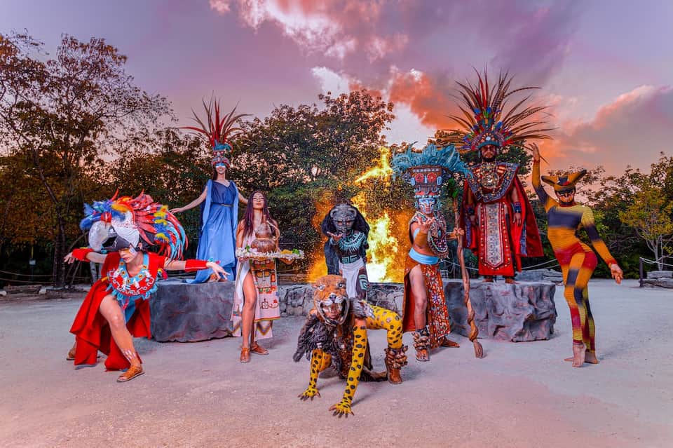 Evening entertainment show with colorful performers in elaborate costumes around fire pit