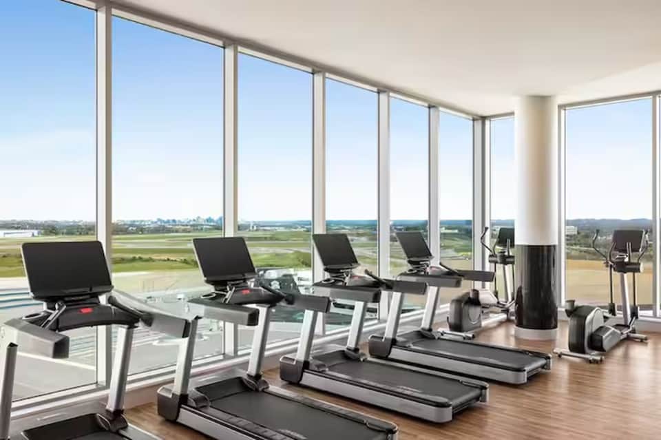 Fitness center with treadmills and exercise equipment overlooking airport runways