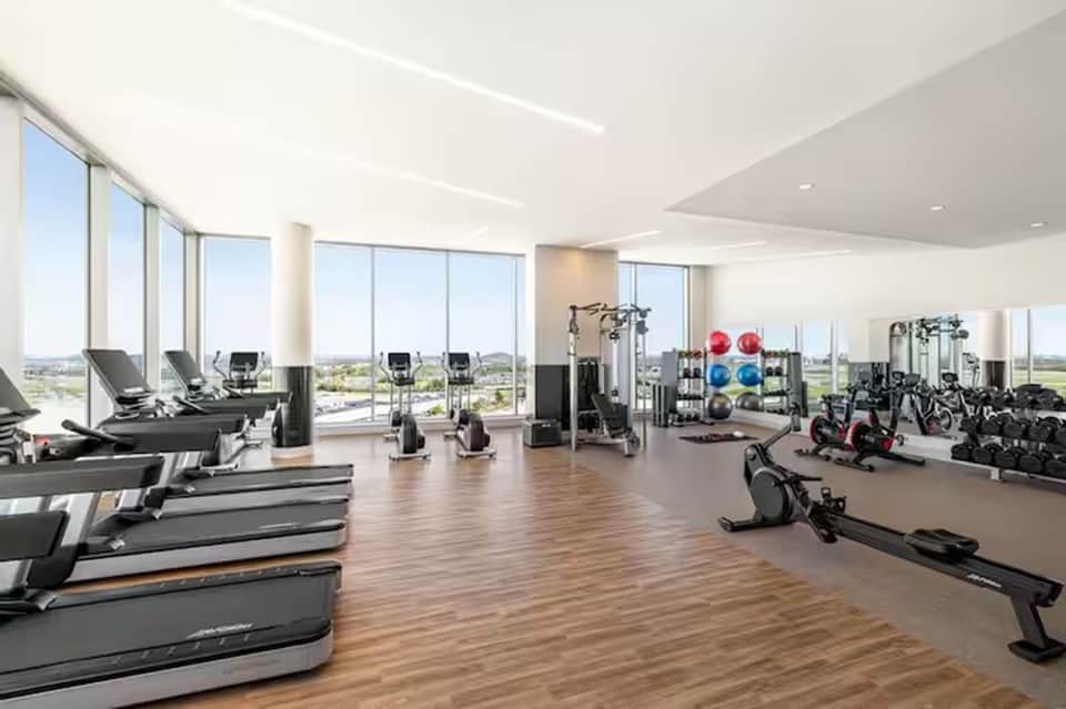 State-of-the-art fitness center with treadmills, exercise bikes, and expansive windows overlooking landscape