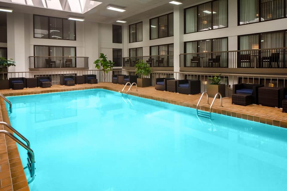 Indoor hotel pool with bright turquoise water and balconies overlooking the natatorium