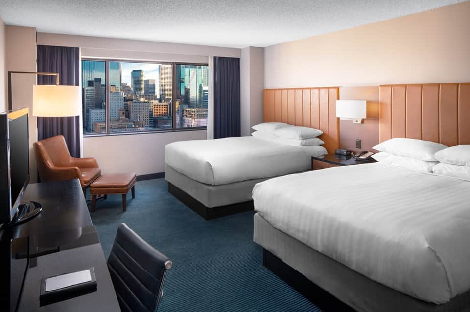 Hotel room with two beds, orange headboards, and city skyline views