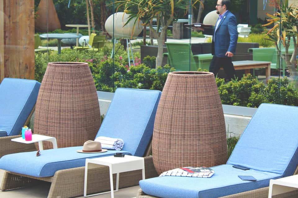 Outdoor lounge area with rattan cabanas, blue cushions, and tropical landscaping