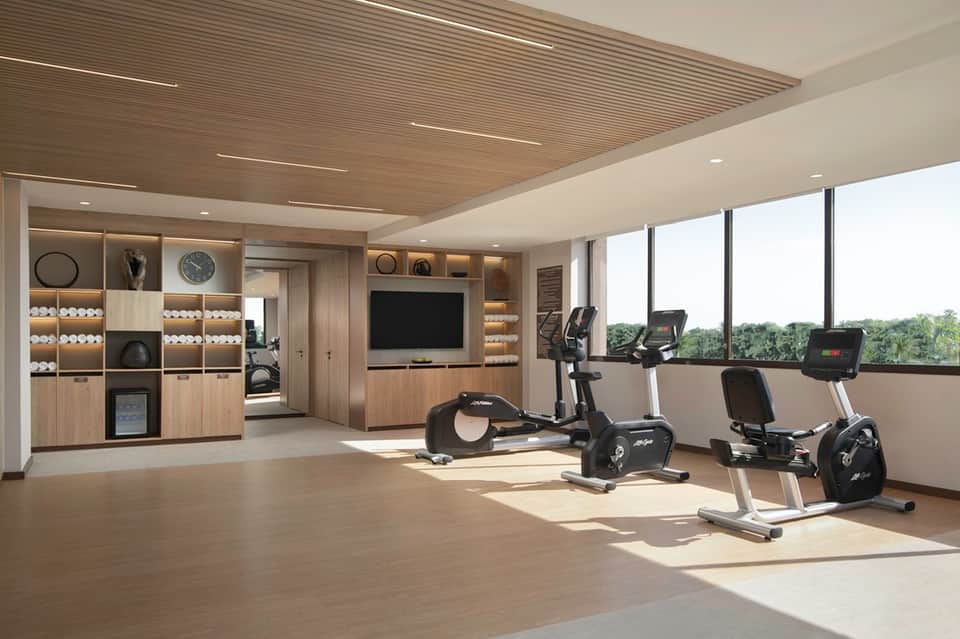 Bright fitness center with exercise bikes, storage, and large windows overlooking grounds
