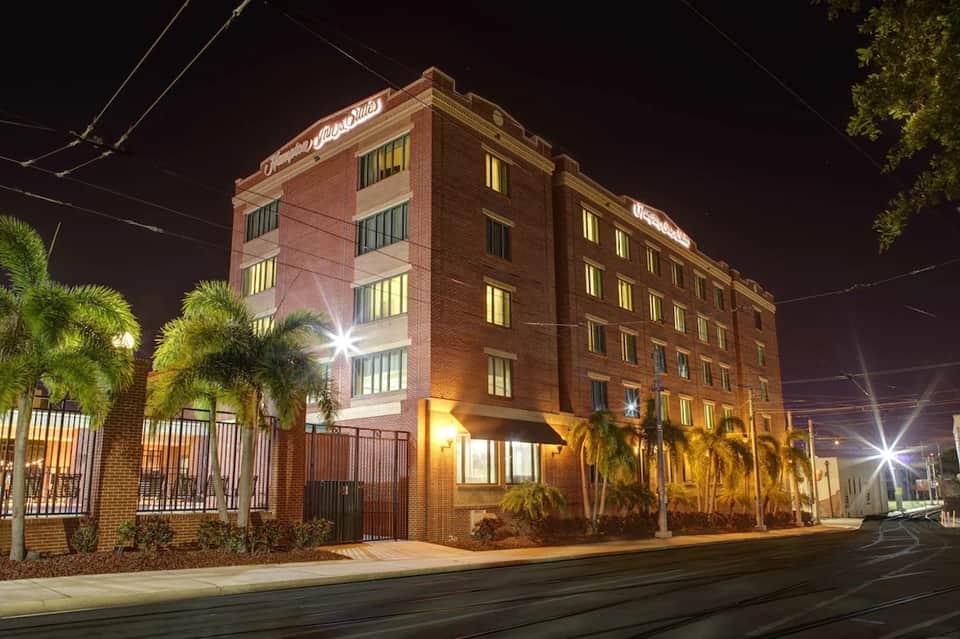 Brick historic hotel building illuminated at night with palm trees and street view