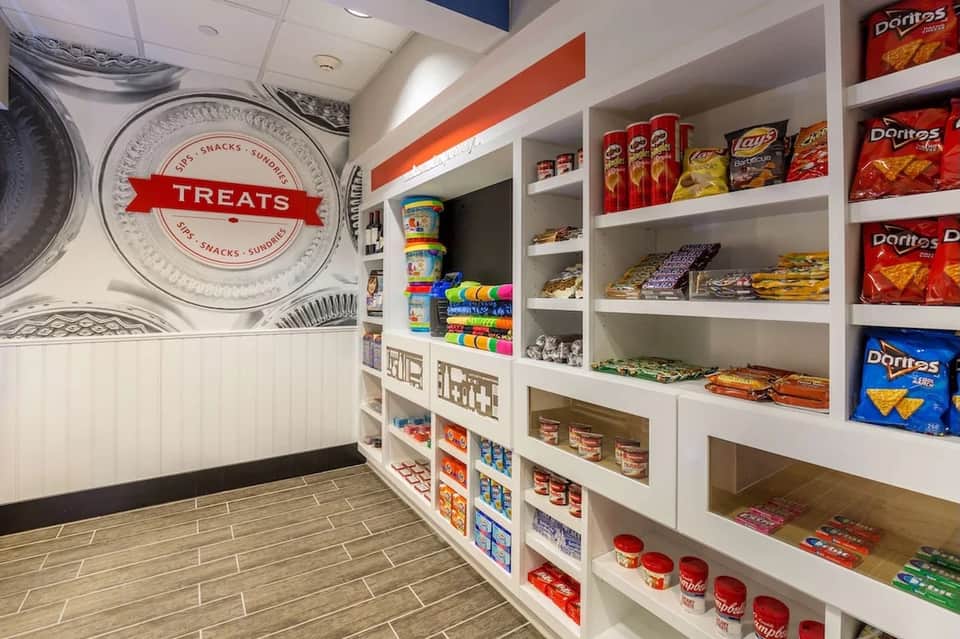 Hotel treats shop interior with white shelving displaying snacks, drinks, and branded merchandise