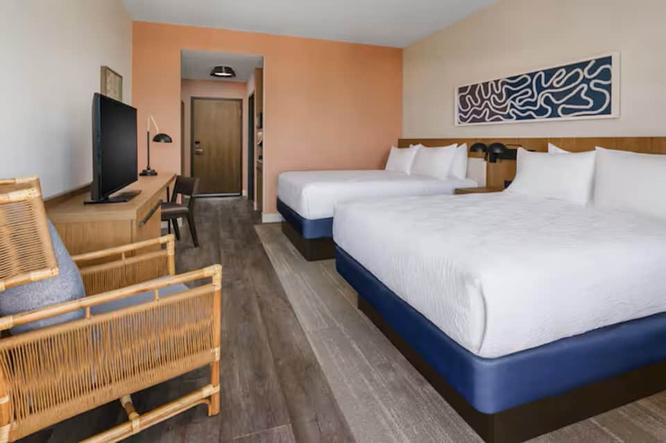 Hotel room with two queen beds, peach accent wall, and modern furnishings