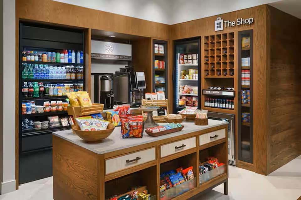 Hotel gift shop interior with wooden cabinetry, beverages, snacks, and merchandise displays