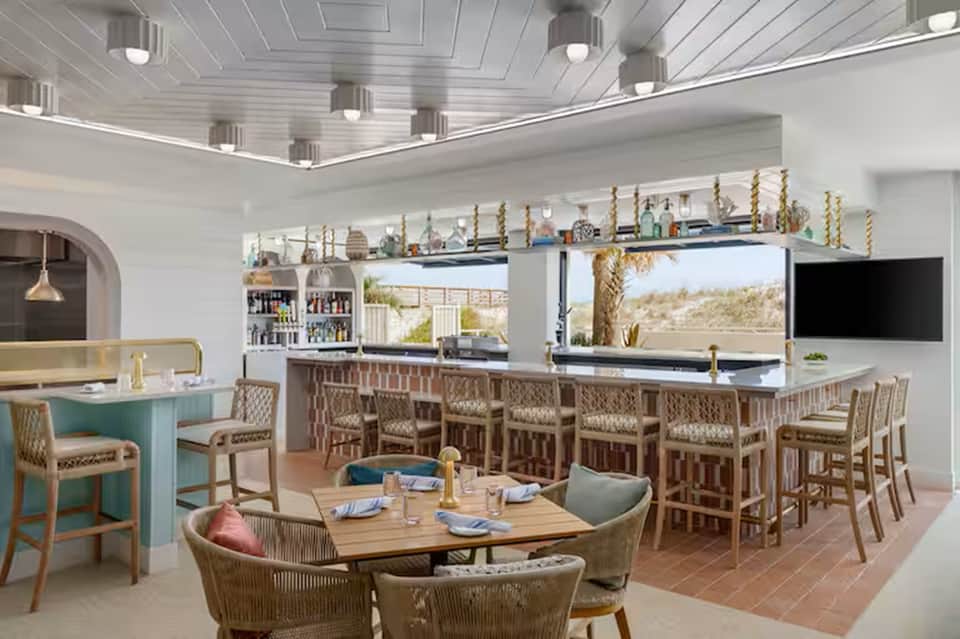 Modern resort restaurant and bar with ocean views, coastal décor, and elegant seating areas