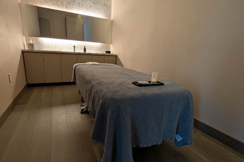Spa treatment room with massage table, vanity sink, and ambient lighting