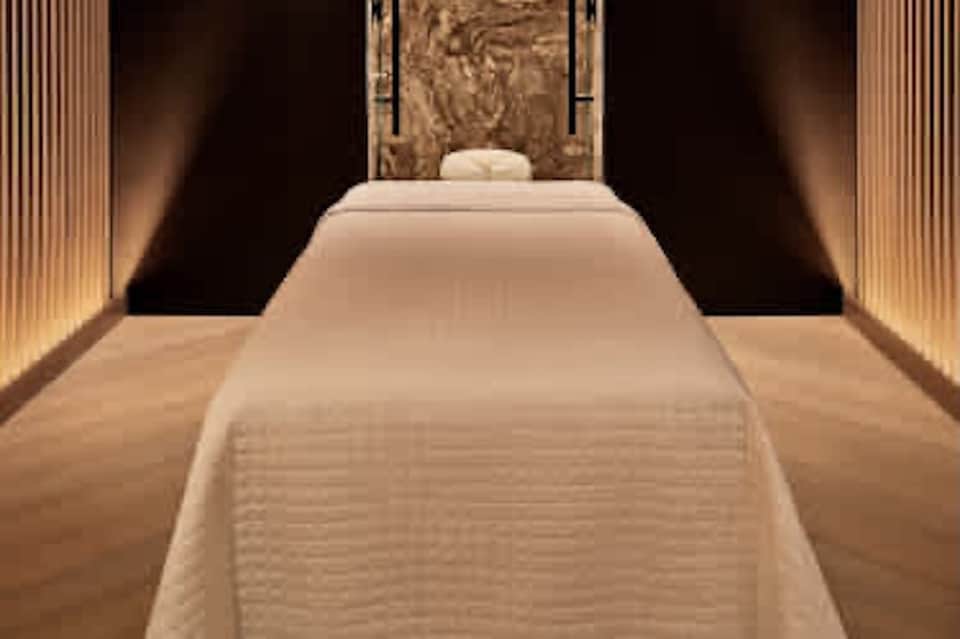 Luxury spa massage room with cream-colored table, warm lighting, and decorative wall panel