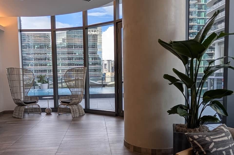 Modern balcony with woven chairs, floor-to-ceiling windows, and city skyline view