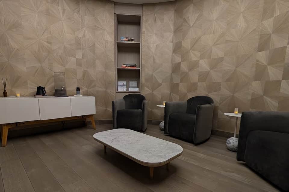 Contemporary spa lounge with geometric wall pattern, black modern chairs, and marble coffee table