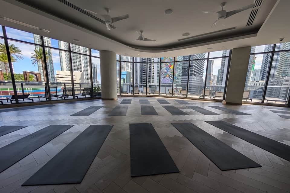 High-rise yoga studio with panoramic city views, floor mats, and floor-to-ceiling windows