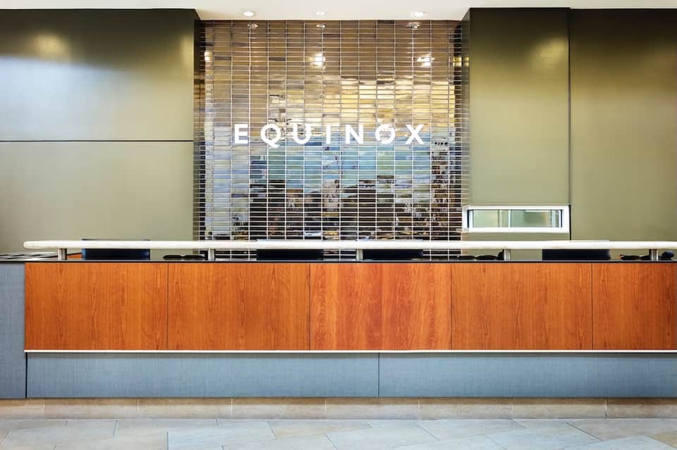Modern hotel reception desk with wooden paneling and Equinox branding