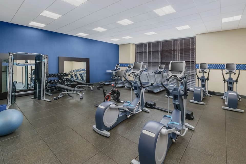 Hotel fitness center with exercise bikes, cardio machines, and free weights on dark flooring