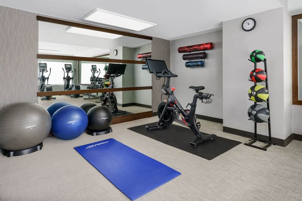 Compact fitness center with exercise bikes, cardio equipment, stability balls, and weight rack