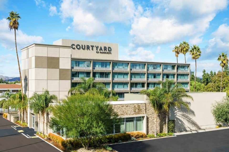 Courtyard by Marriott hotel exterior with modern architecture, palm trees, and stone facade