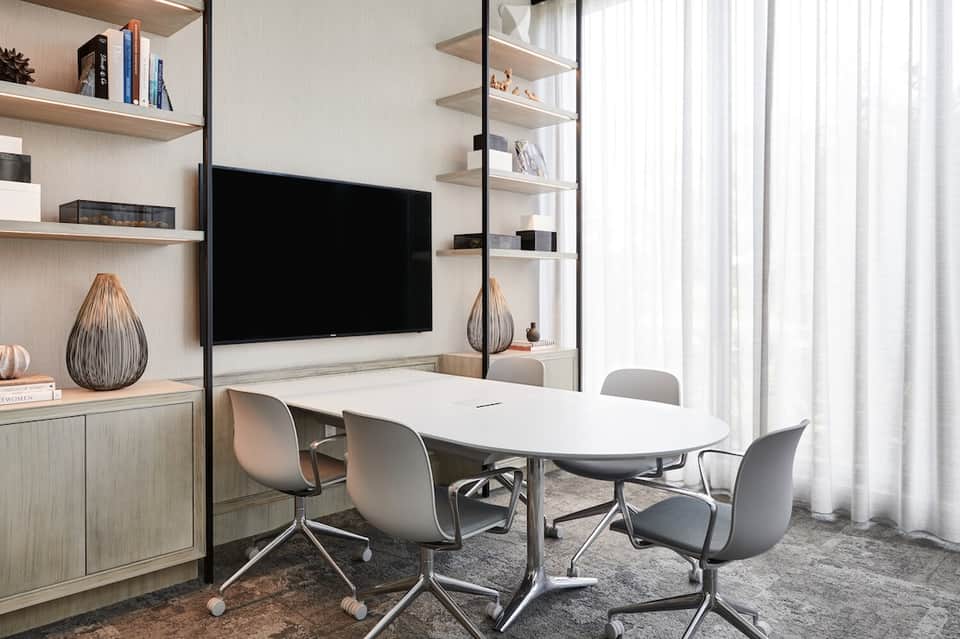 Contemporary conference room with wall-mounted TV, shelving, and modern furnishings
