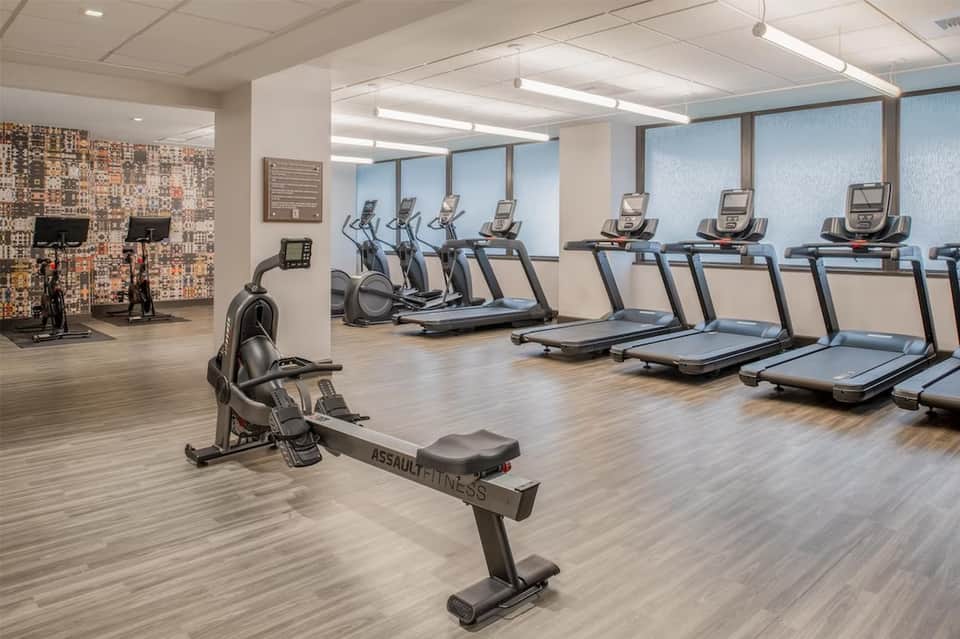 Fitness center with treadmills, elliptical machines, and modern exercise equipment on wooden floor