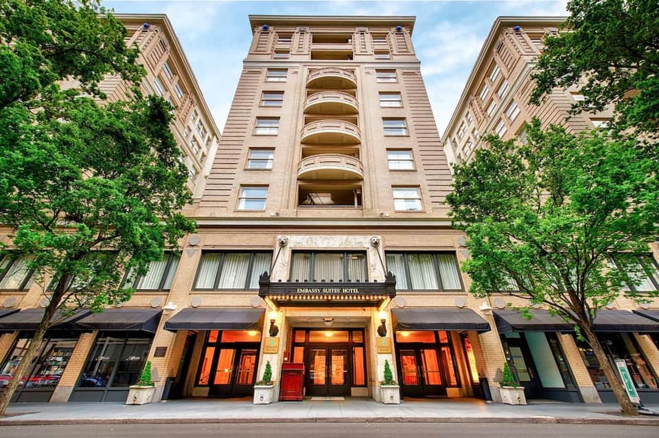 Classic brick hotel facade with red entrance doors, ivy-covered walls, and ornate details