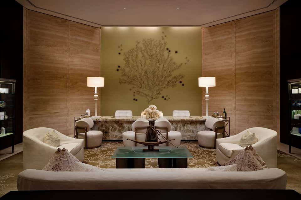 Luxury spa relaxation room with cream seating, marble counter, and nature wall art
