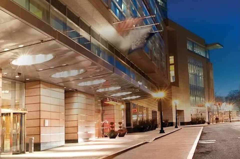 Hotel entrance at dusk with illuminated glass doors and covered portico