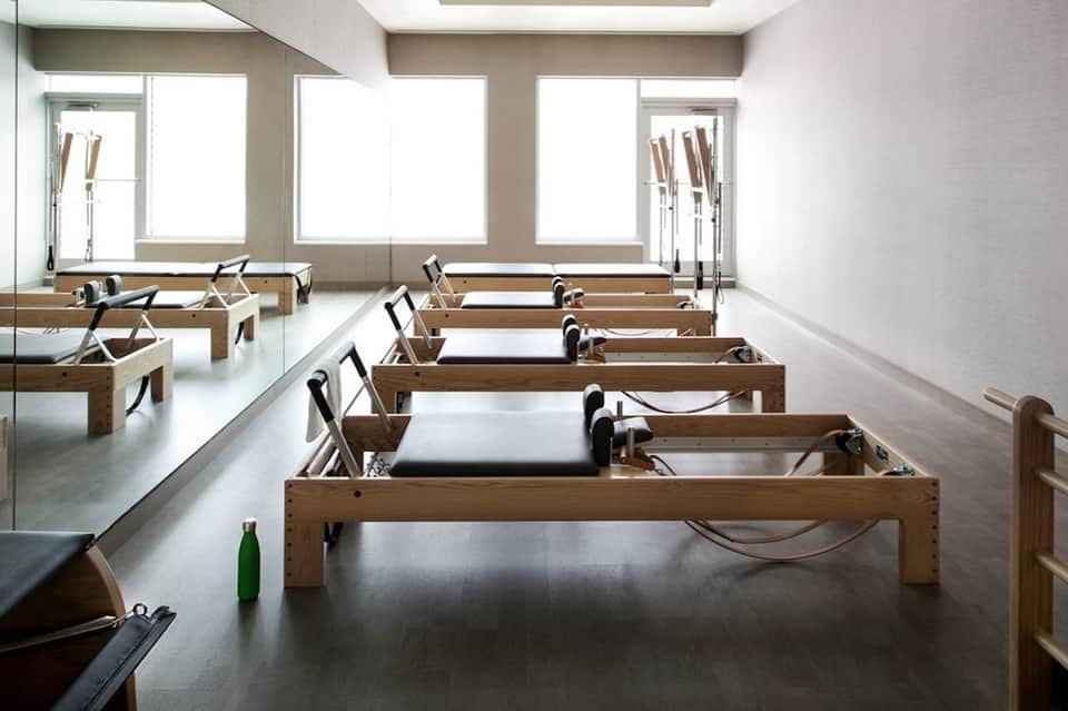 Modern spa treatment room with wooden Pilates reformer machines and natural skylight illumination