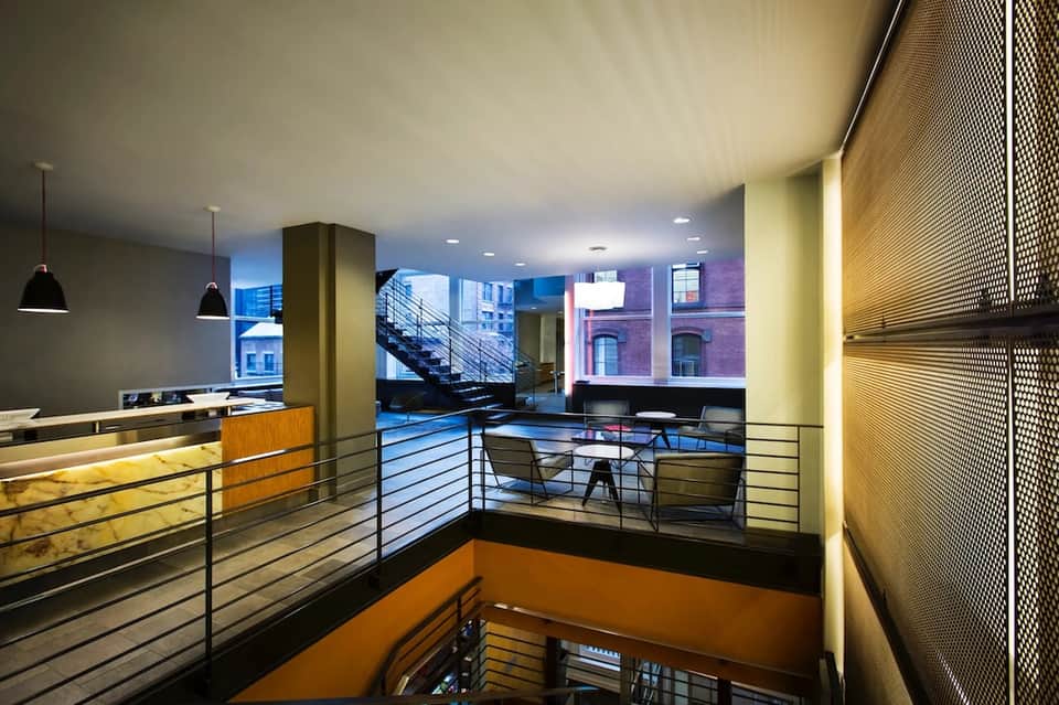 Modern multi-level hotel lobby with staircase, glass railings, and contemporary design