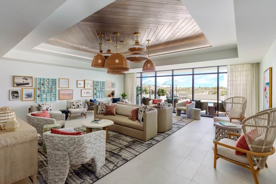 Luxurious living room with cream sofa, woven chairs, ceiling detail, and panoramic windows