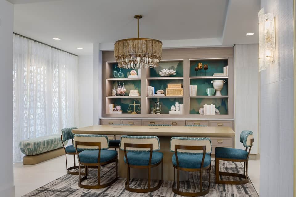 Luxury lounge with teal shelving, desk seating, and elegant chandelier