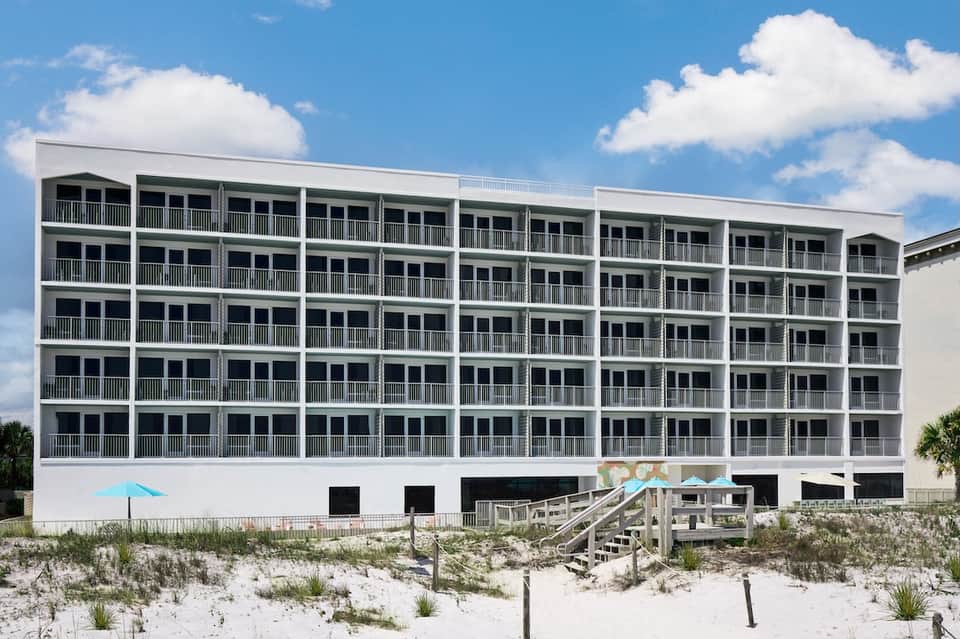 Multi-story beachfront hotel building with repetitive balcony design on sandy beach