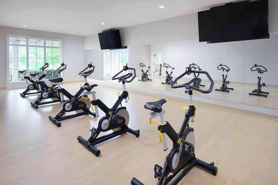 Modern fitness center with rows of stationary bikes, mirrors, and flat-screen TV