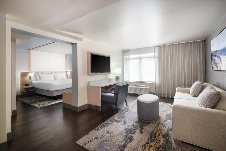 Upscale suite with bedroom, living area, dark wood floors, and contemporary furnishings