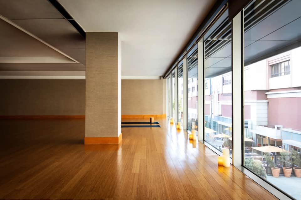 Modern interior hallway with wooden floors, brick columns, and floor-to-ceiling windows