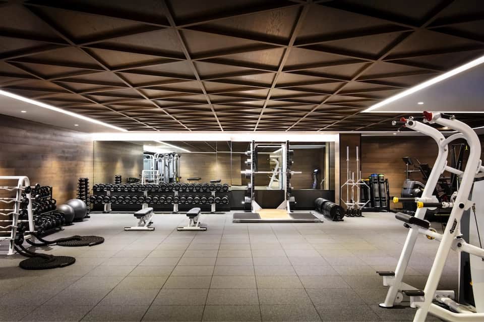 Modern fitness center with dumbbells, cardio equipment, and geometric ceiling design