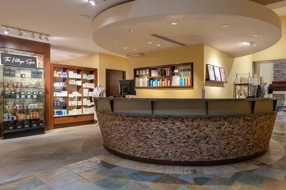 Spa reception area with curved stone desk, product displays, and warm lighting
