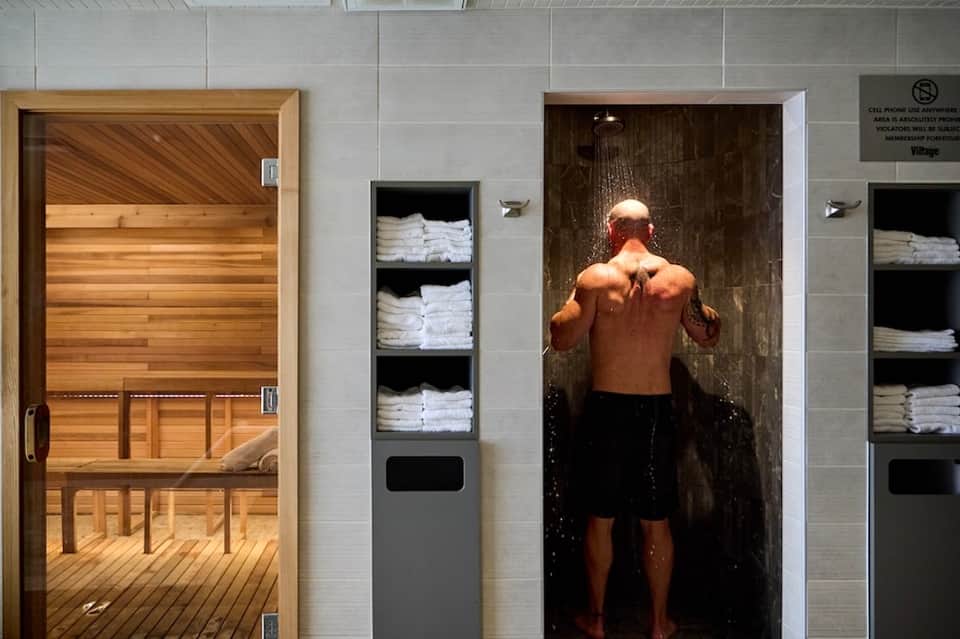 Spa facilities with wooden sauna and rainfall shower next to towel storage